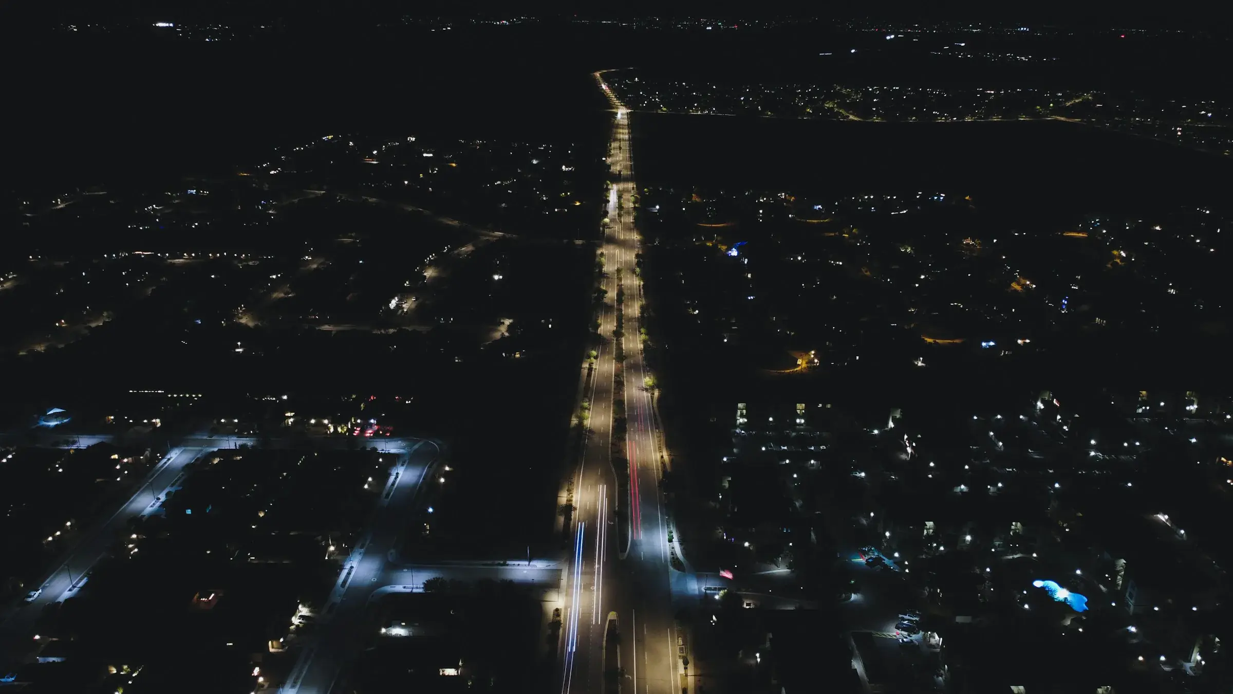 Phoenix at night from the air: a lit arterial road running to the horizon through suburban streets.